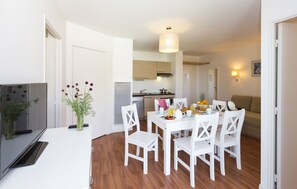 Una cocina moderna con armarios blancos, una mesa de comedor con sillas blancas y una preparación para desayunar.