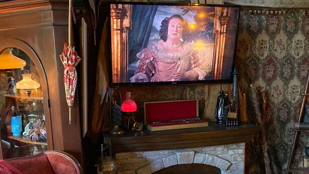 A cozy living room with a fireplace, a television mounted above it, and a plush red sofa. - The Dorm Room (Chickamauga)