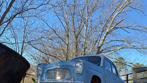 A vintage blue car parked on a driveway with a wooden fence and leafless trees in the background. - The Dorm Room (Chickamauga)
