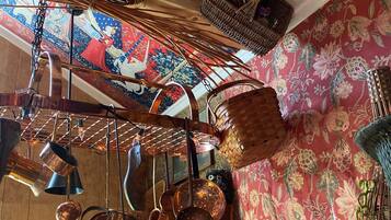 A kitchen with hanging copper cookware, wicker baskets, and a floral-patterned wall.