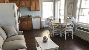 Een moderne keuken met houten kasten, een witte koelkast en een eethoek met witte stoelen en een tafel.