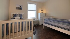 Een slaapkamer met twee enkele bedden, een raam, een verwarming en een dressoir.