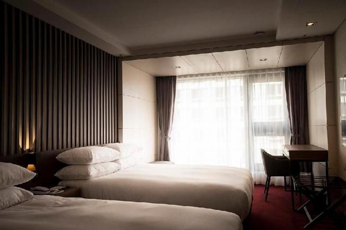 Une chambre d’hôtel avec deux lits, un bureau et une chaise.