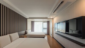 Une chambre d’hôtel avec deux lits, un grand miroir et une télévision.