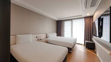 A hotel room with two beds, a TV, and a large window with curtains.