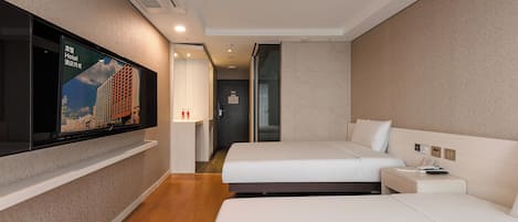 A hotel room with two beds, a TV mounted on the wall, a bedside table, and a door leading to a bathroom.