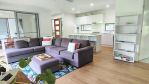 Ein modernes Wohnzimmer mit einem grauen Ecksofa, einem Couchtisch und einem Bücherregal.