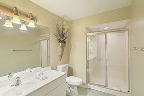 A bathroom with a large mirror, a sink, a toilet, and a glass-enclosed shower. - Amalfi Coast 311A - Gulf View, Heated Community Pool, Exercise Room, Tennis! (Miramar Beach)