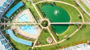 Un resort con diverse piscine, un giardino centrale a forma di cerchio e un ponte che collega varie zone.