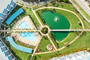 Un resort con varias piscinas, un jardín circular central y un puente que conecta diferentes zonas.