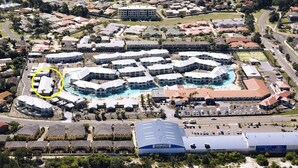 Eine Luftaufnahme eines Resorts mit mehreren Gebäuden, die um einen zentralen Poolbereich angeordnet sind.