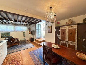 Amplia sala de estar con mesa de comedor de madera, un candelabro y una escalera que conduce a un nivel superior.