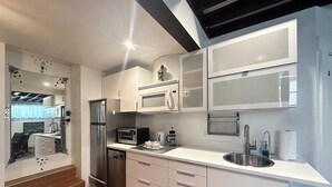 Une cuisine moderne avec des meubles blancs, des appareils en acier inoxydable et une grande fenêtre.