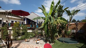 Un espace patio avec un parasol rouge, une petite chaise rouge et un trampoline.