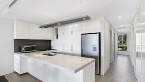 A modern kitchen with white cabinetry, a stainless steel refrigerator, a built-in microwave, and a water dispenser. - Cote D Azur in the heart on Nelson Bay with a swimming pool (Nelson Bay)