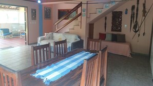 Une pièce comprenant une table à manger en bois, des chaises, un canapé et un escalier menant à un autre niveau.