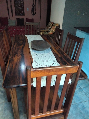 Een eetgedeelte met een houten tafel, stoelen en een kantkleed.