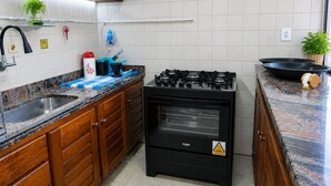 Une cuisine équipée d’une cuisinière à gaz, de meubles en bois, d’un évier et d’un plan de travail recouvert de carreaux.