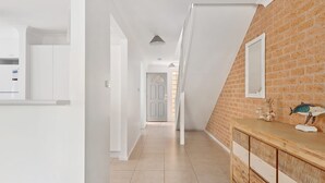 A hallway with a wooden counter and a mirror, leading to a door. - Walking Distance to Little Beach and Shoal Bay (Nelson Bay)