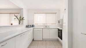 A modern kitchen with white cabinets, a dishwasher, a microwave, and an oven. - Walking Distance to Little Beach and Shoal Bay (Nelson Bay)
