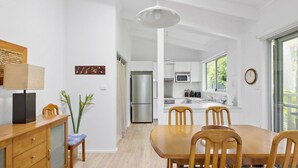 A modern kitchen with white cabinets, stainless steel appliances, and a large window. - Hidden Oasis Pet Friendly In Anna Bay (Anna Bay)