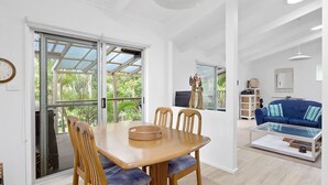 A spacious living area with a dining table, chairs, a sofa, and a TV. - Hidden Oasis Pet Friendly In Anna Bay (Anna Bay)
