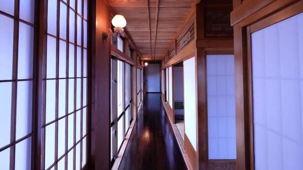 Un pasillo con suelo de madera y amplias ventanas a ambos lados.