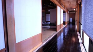 Un pasillo japonés tradicional con tatamis, suelo de madera y puertas correderas.