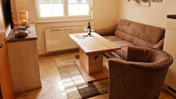 Una sala de estar acogedora con un sofá, una mesa de centro y un televisor sobre un mueble.