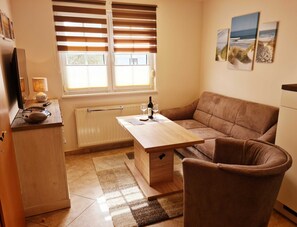 A cozy living room with a sofa, a coffee table, and a TV on a stand.
