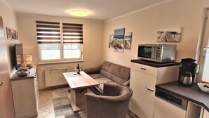 Una cocina compacta con microondas, cafetera y una pequeña mesa de comedor.