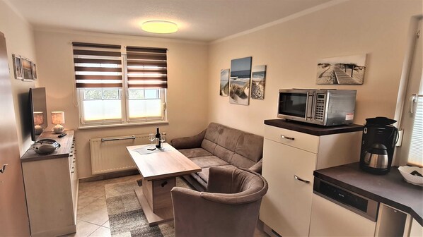 A compact kitchen with a microwave, coffee maker, and a small dining table.