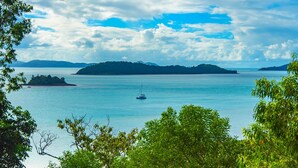 Eine friedliche Küstenlandschaft mit freier Sicht auf eine kleine Insel und ein Segelboot in der Ferne.