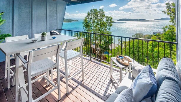 Ein Balkon mit Meerblick, einem Esstisch und einer Couch.