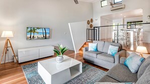 Ein modernes Wohnzimmer mit einem grauen Sofa, einem weißen Couchtisch und einem Strandbild.