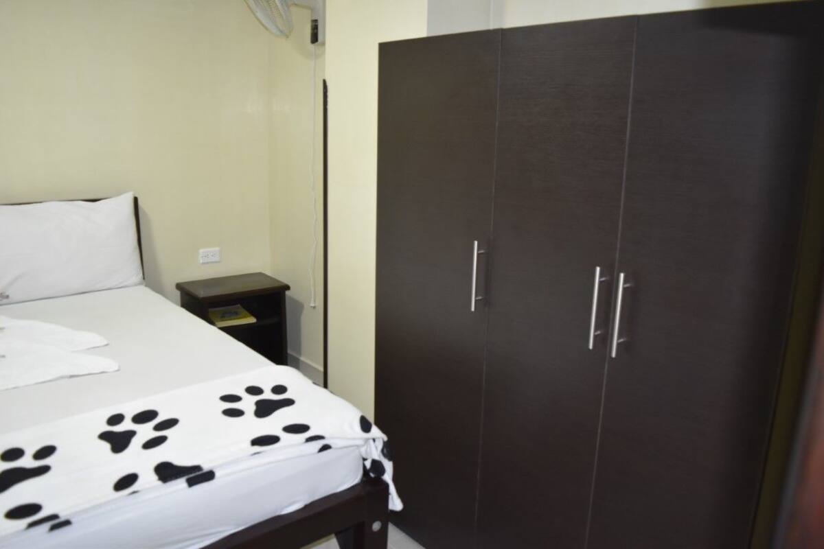Un dormitorio con cama, armario, mesita de noche y calentador de pared.