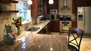 A modern kitchen with granite countertops, stainless steel appliances, and dark wooden cabinets. - Super Location. Close to about everywhere .Great value.Over 200 reviews!! (Richmond)