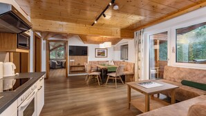 A modern kitchen with a microwave, stove, and oven, a dining area with a table and chairs, and a cozy living room with a sofa and a window. - Apartment Sterngucker - Guesthouse Herrmann (Filzmoos)