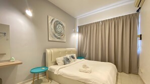 A bedroom with a bed, a bedside table, a small stool, a wall-mounted artwork, and a window with curtains. - Arcadia Penang by Plush (George Town)