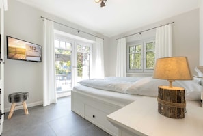 Une chambre à coucher avec un lit, un téléviseur fixé au mur et une lampe sur une table de chevet.