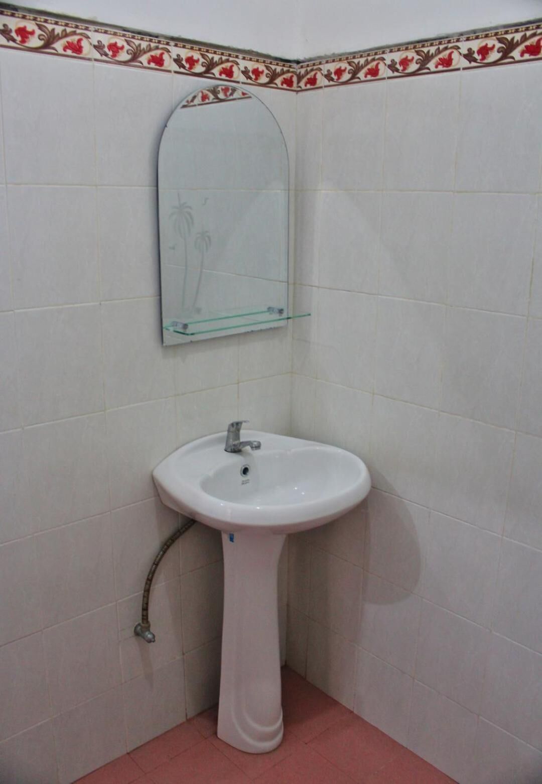 Casa de banho nos fundos com uma pia branca, espelho e uma moldura de azulejos decorativos.