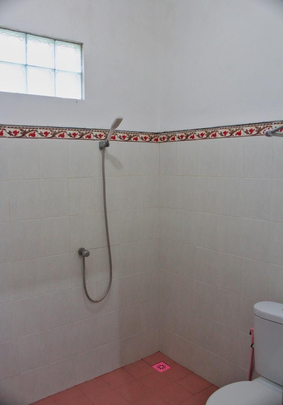 Um banheiro pequeno com chuveiro, vaso sanitário e janela.