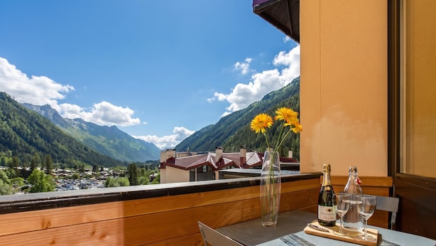 A balcony with a table set for two, a bottle of champagne, and a vase with flowers. - Grand Roc C411 280m from Slopes, Mont-Blanc View, Parking & WiFi, Argentière (Chamonix), France (Argentière (Chamonix))