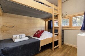 A bunk bed room with a window, a heater, and a small desk.