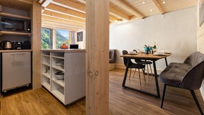 A modern kitchen with a microwave, kettle, and coffee maker, a dining area with a table and chairs, and a view of the outdoors. - Grand Roc C411 280m from Slopes, Mont-Blanc View, Parking & WiFi, Argentière (Chamonix), France (Argentière (Chamonix))