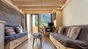 A modern interior with a sofa, a small table, and a desk with a computer. - Grand Roc C411 280m from Slopes, Mont-Blanc View, Parking & WiFi, Argentière (Chamonix), France (Argentière (Chamonix))