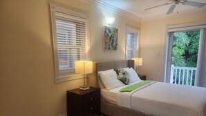 Et hotelværelse med en seng, to sengeborde, en lampe på hvert bord, et billede og udsigt til grønne områder ude af vinduet.