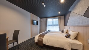 Una habitación de hotel con una cama grande, un escritorio y un televisor montado en la pared.