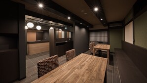 Un interior moderno con mesas y sillas de madera, iluminación empotrada y una zona de recepción.