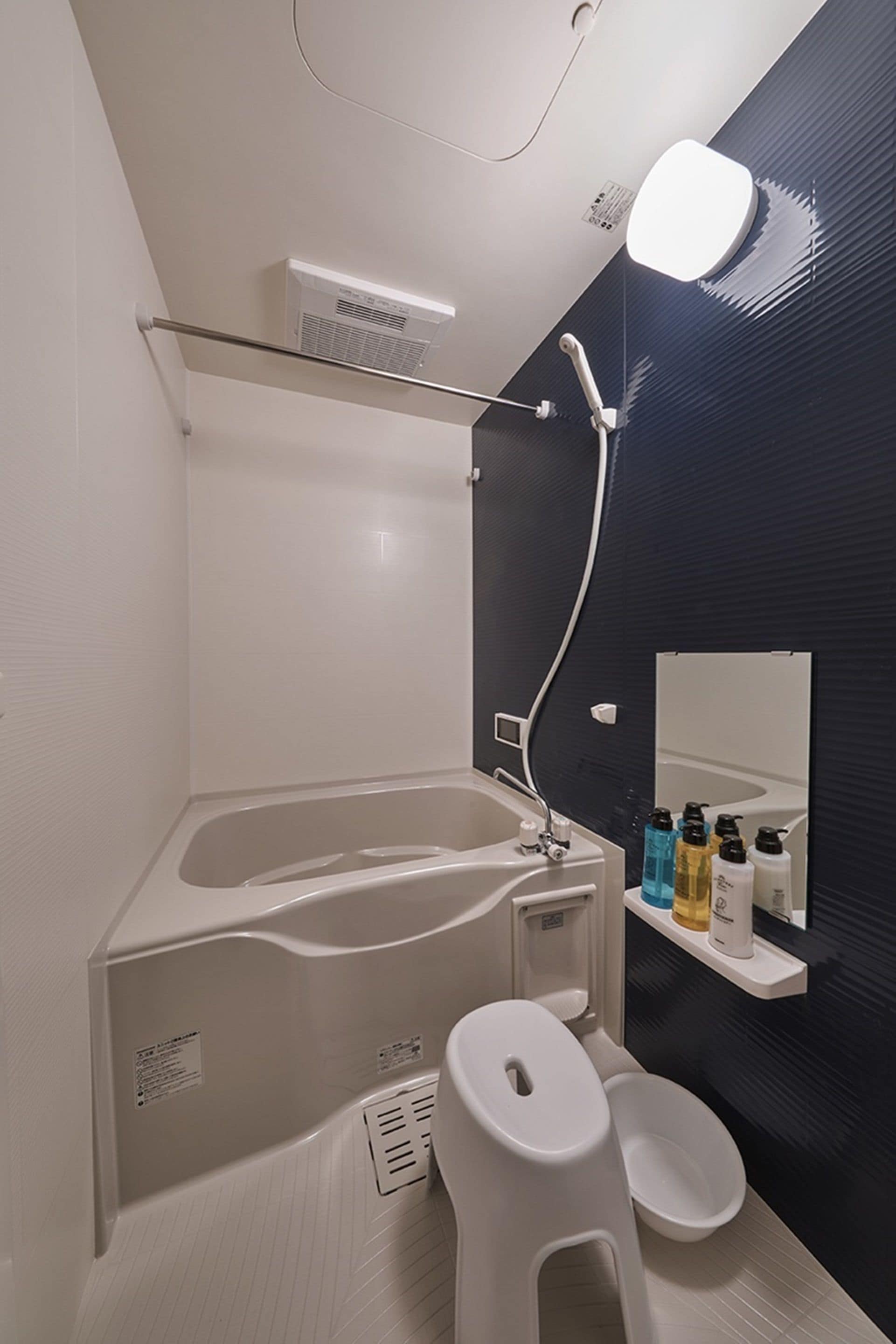 Ein modernes Badezimmer mit Badewanne, Toilette und Waschbecken. Über dem Waschbecken hängt ein Spiegel und über der Badewanne ein Duschkopf.